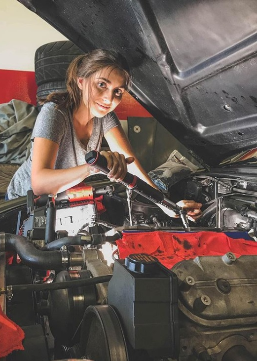 Técnica realizando mantenimiento en el motor de un vehículo